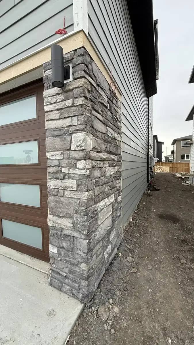 Garage apron concrete framed by grey stone pillars and exterior driveway approach