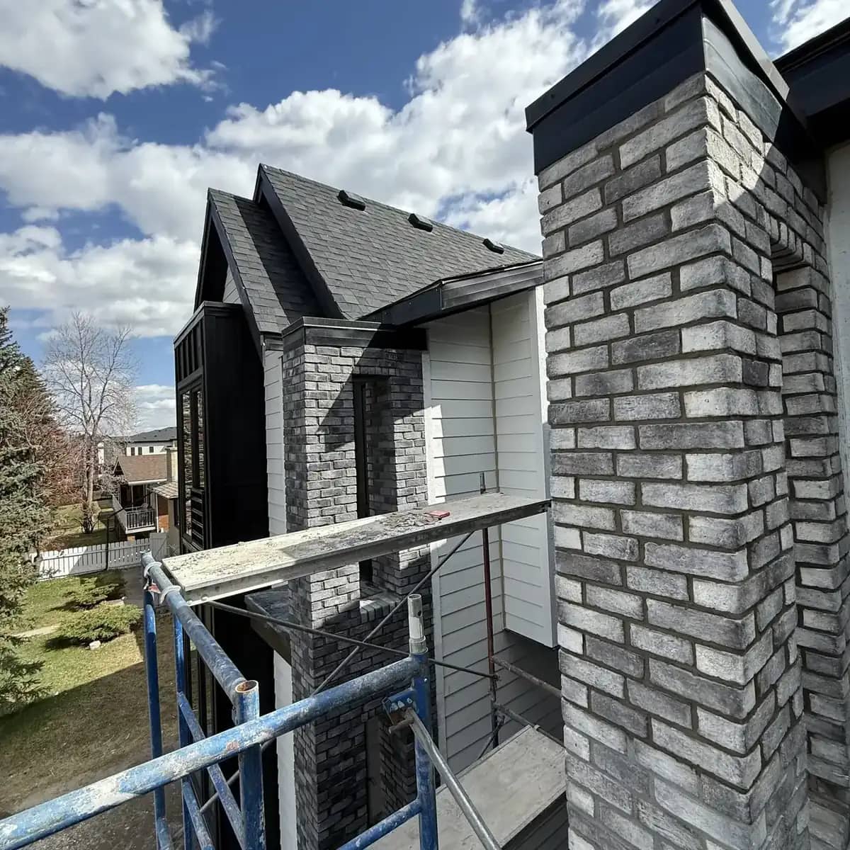 Modern duplex exterior with grey stone entry columns, black and white siding, and concrete steps