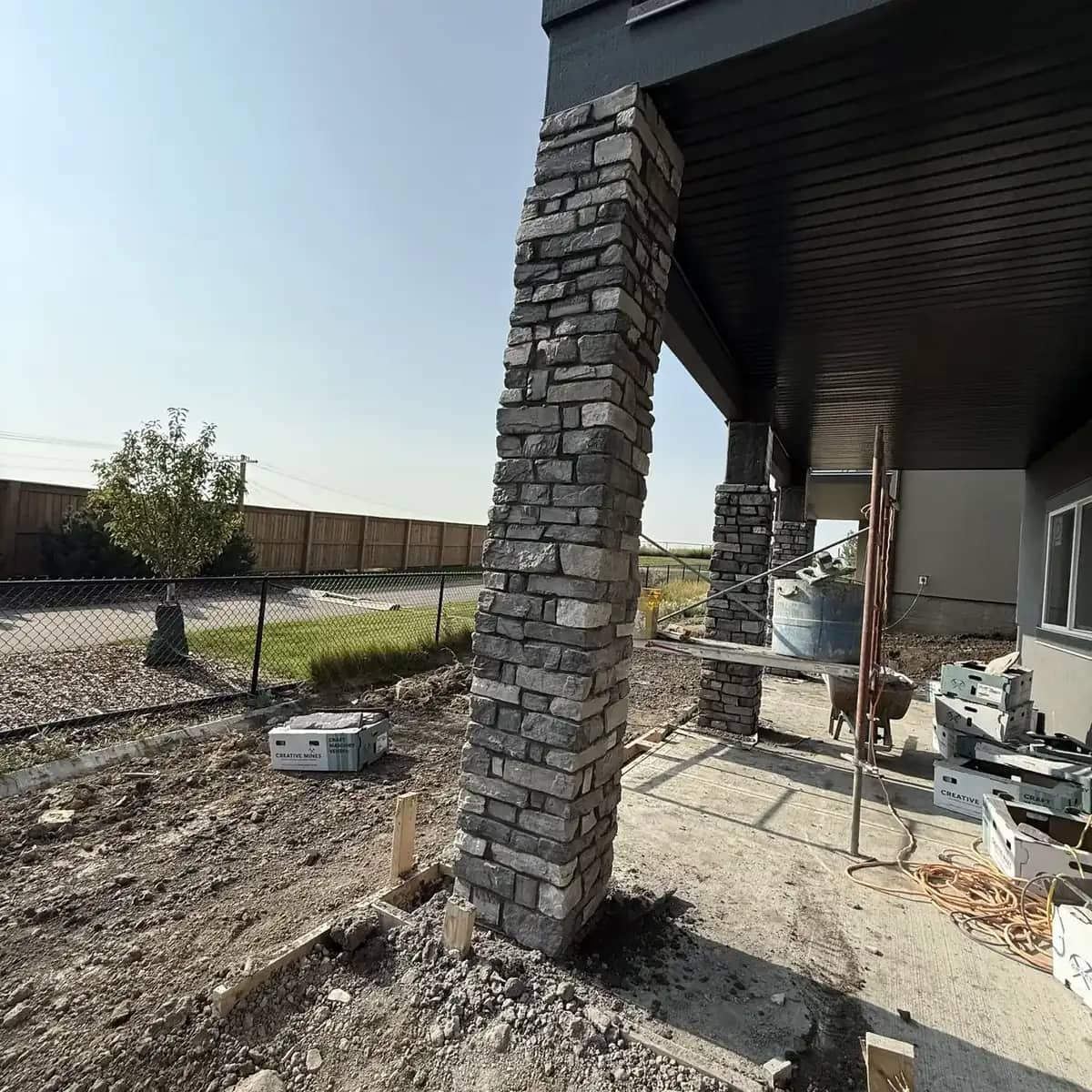 Stacked grey stone garage return beside a residential garage opening and driveway approach