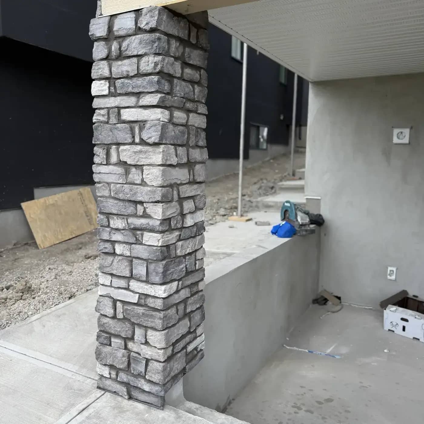 Stone column beside concrete entry wall and slab transition