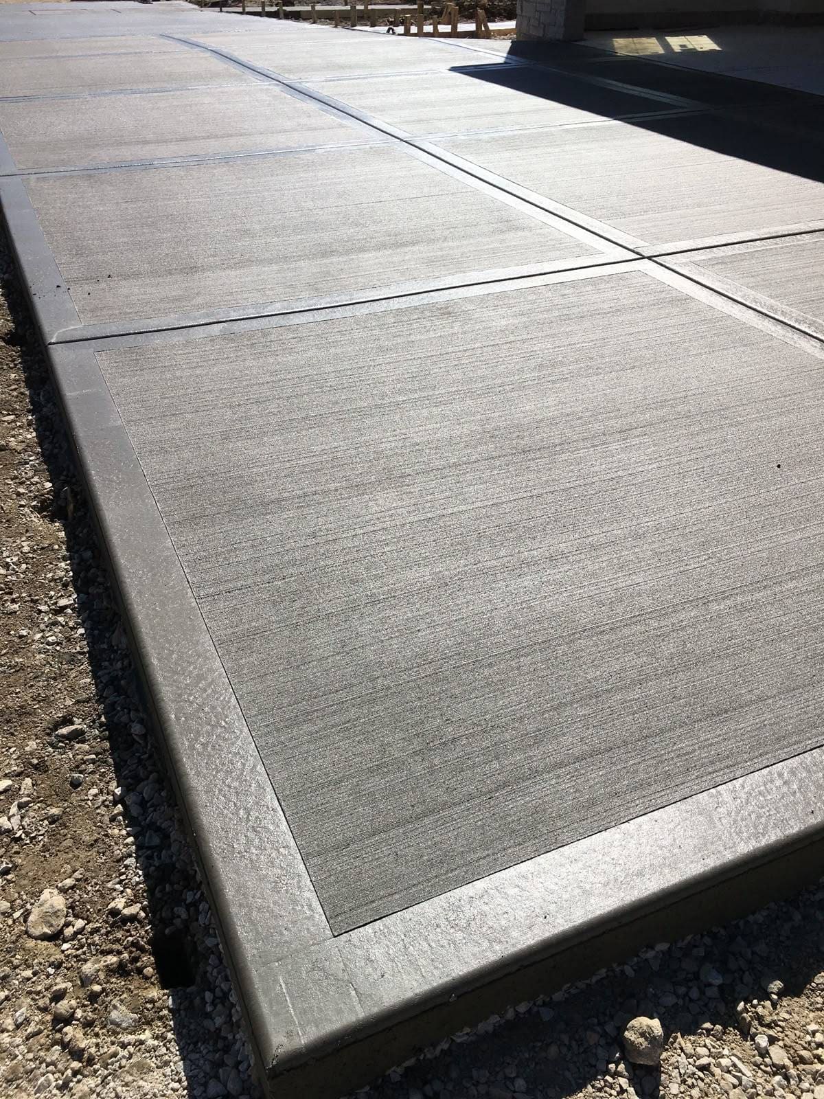 Close view of broom-finished concrete sidewalk surface with clean edge lines