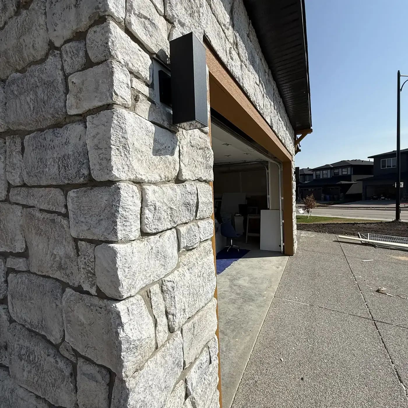 Exterior concrete surface beside a garage wall and white stone column