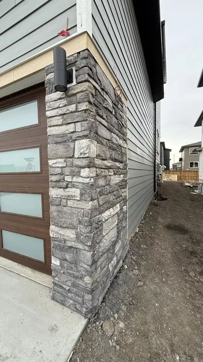 Garage apron concrete framed by grey stone pillars and exterior driveway approach