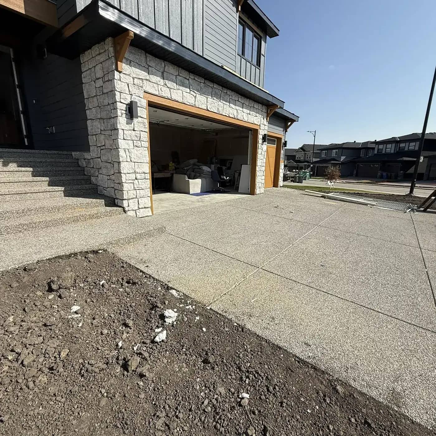 Large exposed aggregate driveway with stone garage accents