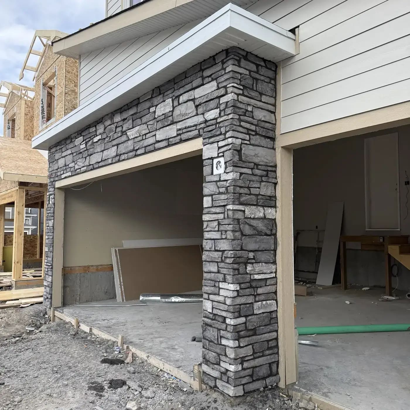 Grey stacked stone column and garage header stonework on a new residential build