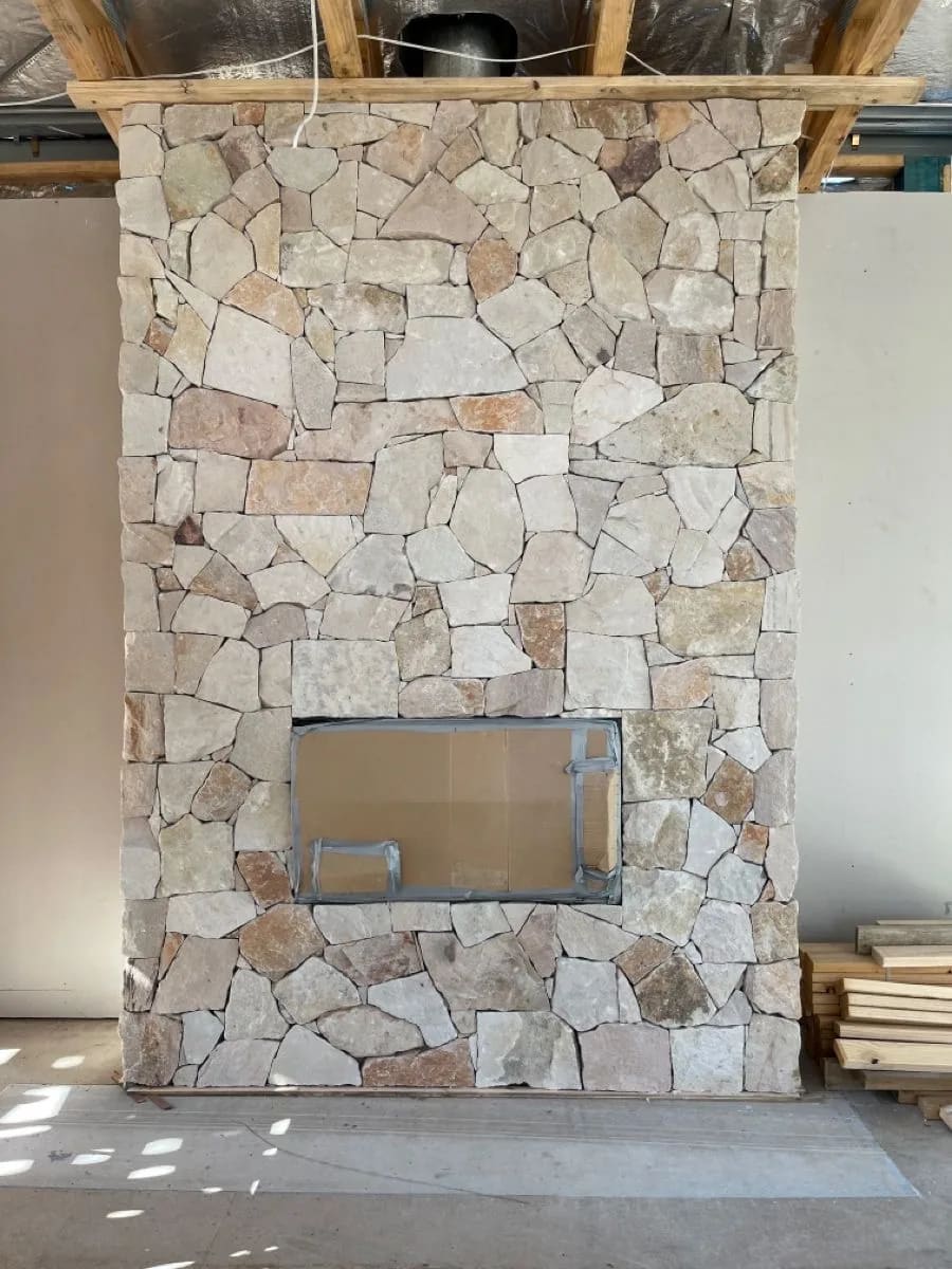 Interior stone fireplace feature wall with natural light stone around a rectangular fireplace opening
