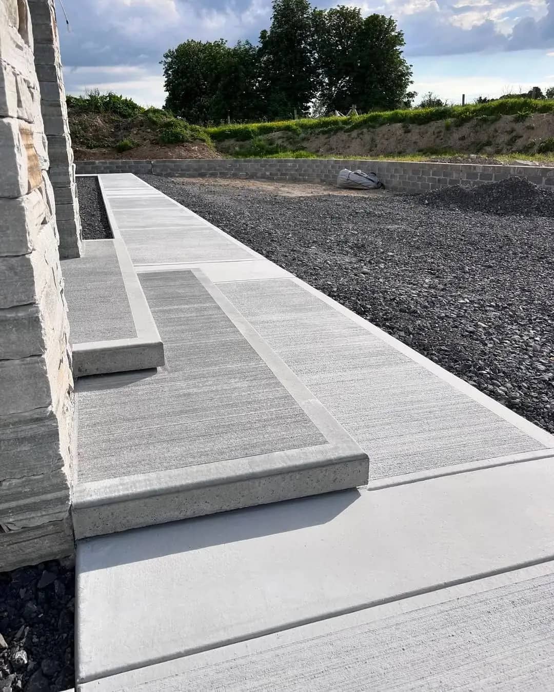 Long broom-finished concrete walkway beside a house exterior