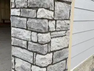 Garage driveway apron concrete with stone pillars and residential garage opening