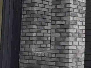 Grey thin brick entry columns with stacked courses, corner returns, and concrete entry slab